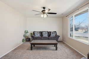 Carpeted living room with a ceiling fan and a textured ceiling