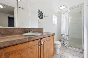 Full bath featuring a shower stall, vanity, and light tile patterned floors