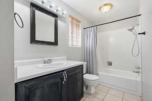 Bathroom featuring vanity, shower / bath combo, and light tile patterned floors