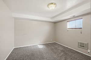 Carpeted spare room with a textured ceiling and heating unit