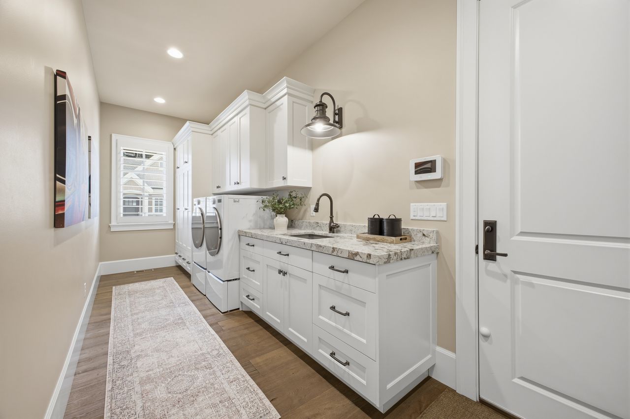 Main Floor Laundry room featuring dark wood-style flooring, separate washer and dryer, cabinet space, and recessed lighting