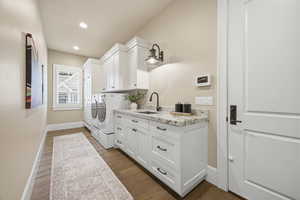 Main Floor Laundry room featuring dark wood-style flooring, separate washer and dryer, cabinet space, and recessed lighting