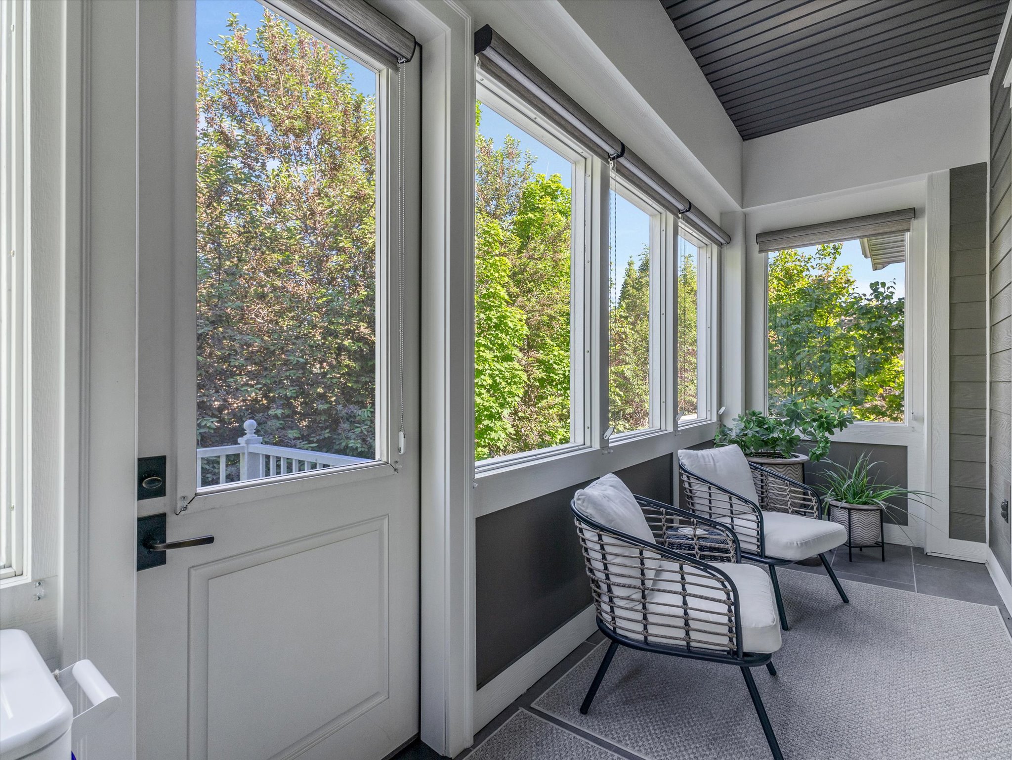 Sunroom with multiple windows, a paneled door with black hardware, and a dark tile floor