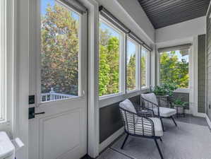Sunroom with multiple windows, a paneled door with black hardware, and a dark tile floor