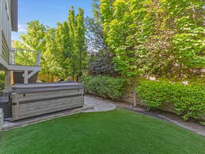 Backyard featuring a hot tub on a paver patio with a low retaining wall