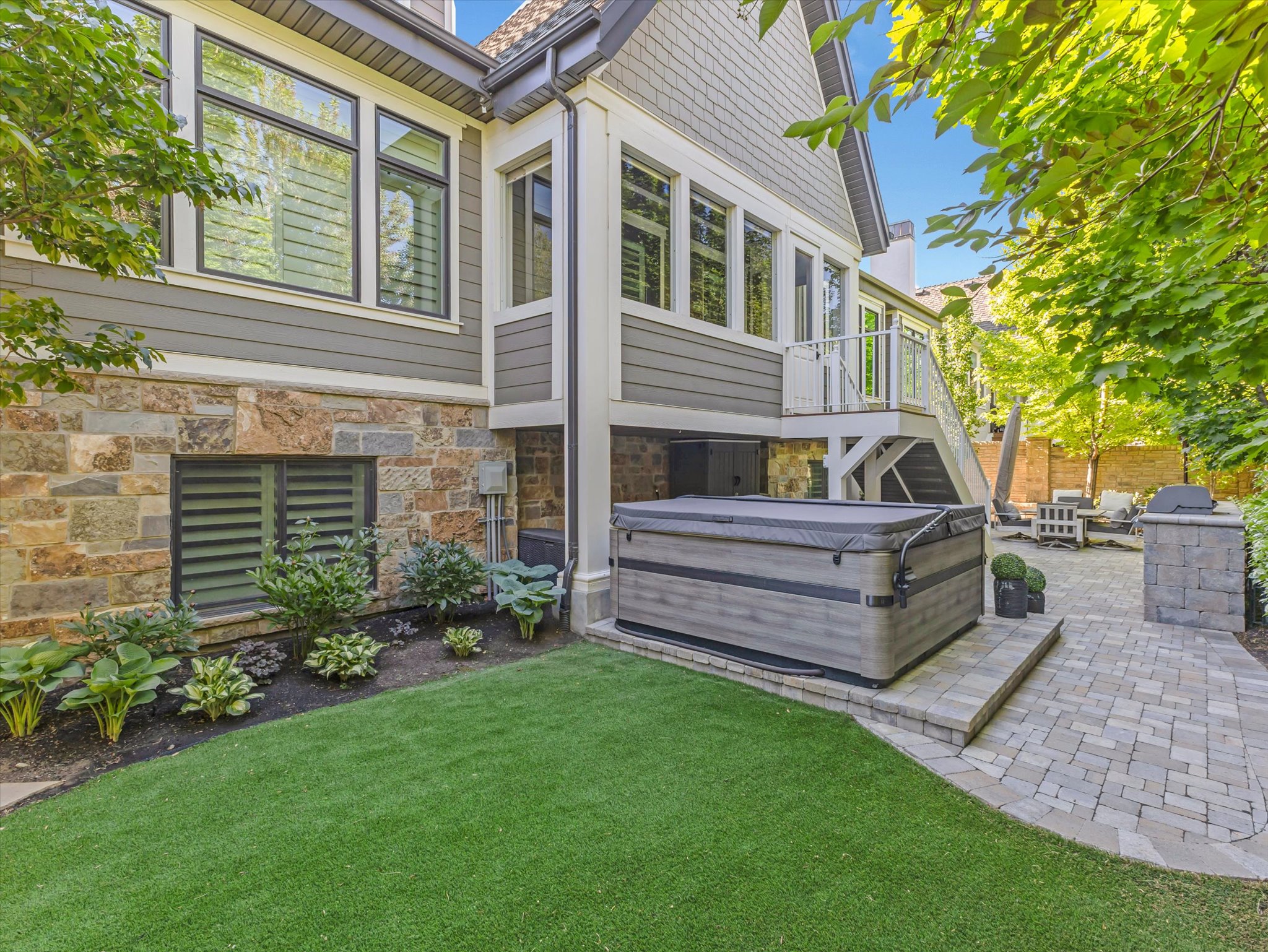 Outdoor spa area featuring a paver patio, a built-in outdoor spa, and a stone-clad exterior with horizontal siding