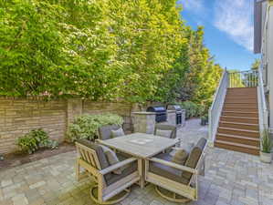 Paver patio featuring a stone veneer privacy wall and built-in outdoor kitchen with grill stations