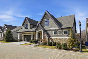 Craftsman inspired home featuring stone siding, concrete driveway, covered porch, and roof with shingles