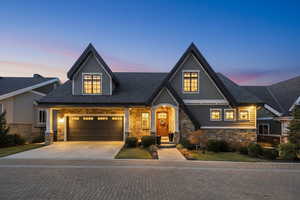 View of front of house featuring stone siding, driveway, and a garage