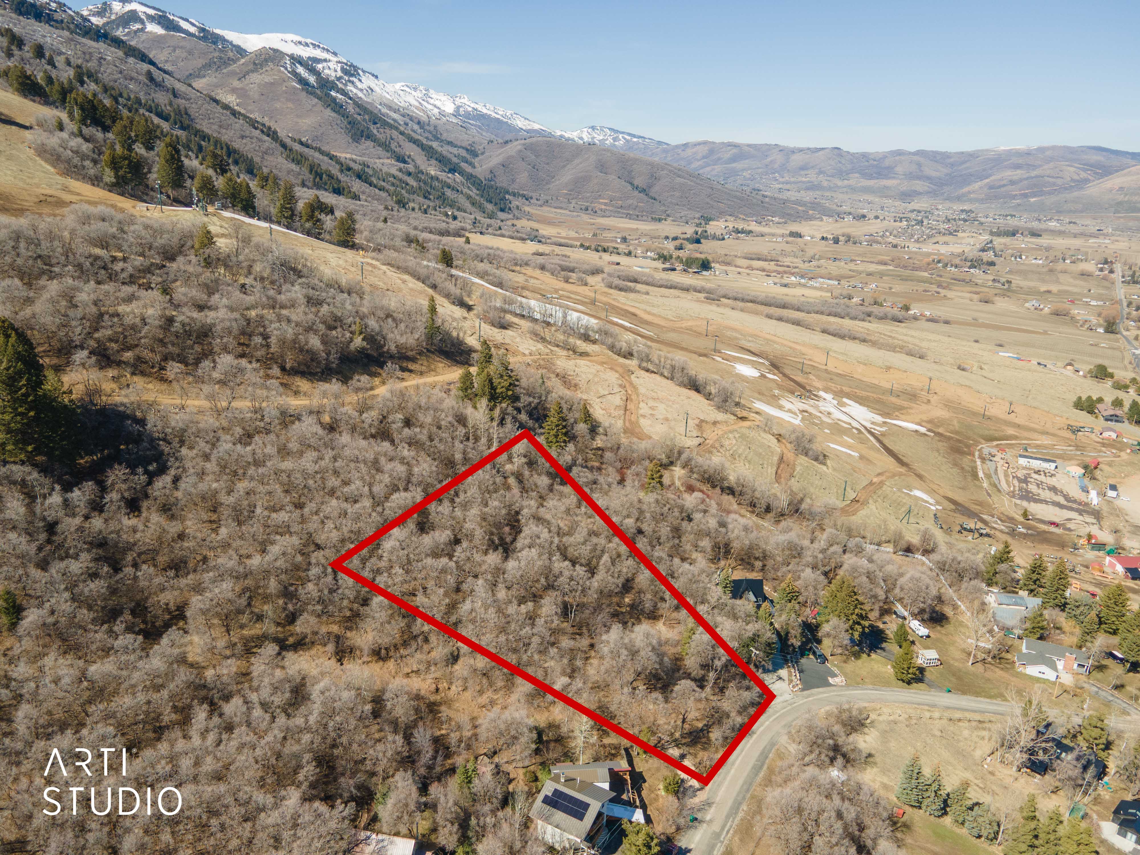 Aerial view of sparsely populated area with property boundaries highlighted and a mountainous background