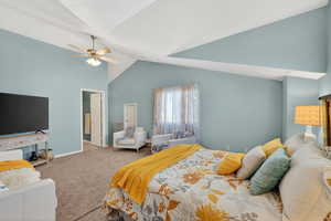 Carpeted bedroom featuring lofted ceiling and a ceiling fan