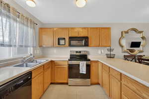 Kitchen featuring black appliances, light countertops, and light tile patterned floors