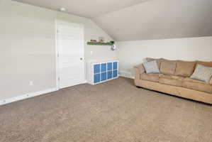 Living area featuring carpet flooring and vaulted ceiling