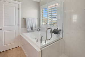 Full bath featuring a bath, light tile patterned flooring, and a stall shower