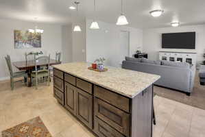 Kitchen with a kitchen island, light stone countertops, open floor plan, dark wood finish cabinetry, and a breakfast bar