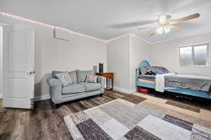 Bedroom with dark wood-style flooring, a ceiling fan, and a textured ceiling