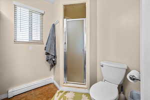 Full bathroom featuring a baseboard radiator, a shower stall, and light tile patterned floors