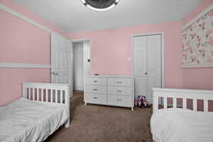 Bedroom with dark carpet, a textured ceiling, and a closet