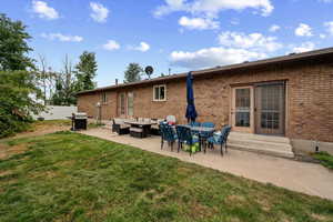 Rear view of property with entry steps, brick siding, a patio, and outdoor lounge area