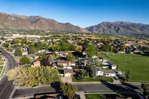 Aerial view of property and surrounding area featuring a mountainous background and nearby suburban area