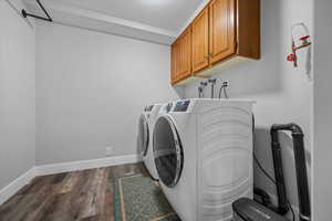 Laundry room with dark wood-style flooring, a textured ceiling, washer and clothes dryer, and cabinet space