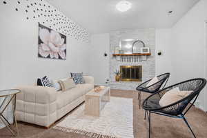 Carpeted living room with a brick fireplace and a textured ceiling