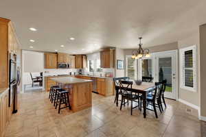 Kitchen featuring a kitchen island, hanging lights, a textured ceiling, light stone countertops, and tasteful backsplash