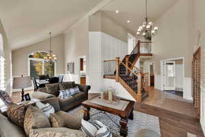 Living area with hanging lights, wood finished floors, lofted ceiling, and a wainscoted wall