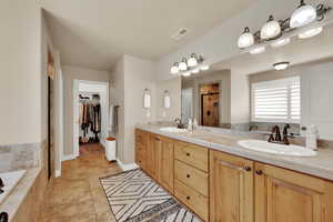 Full bath with a stall shower, double vanity, a walk in closet, and a garden tub