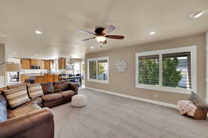 Living area featuring ceiling fan, light colored carpet, hanging lights, and a textured ceiling