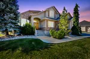 View of front facade with stone siding, a front yard, and stucco siding