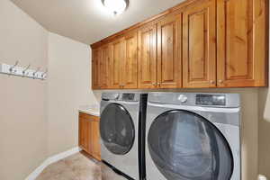 Laundry room with cabinet space, washer and clothes dryer, a textured ceiling, and light tile patterned floors