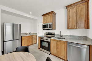 Kitchen featuring stainless steel appliances, light stone counters, a textured ceiling, recessed lighting, and light tile patterned floors