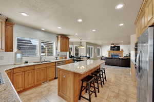 Kitchen with open floor plan, backsplash, a center island, light stone countertops, and stainless steel appliances