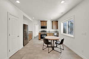 Kitchen with light countertops, stainless steel appliances, recessed lighting, a textured ceiling, and wood finish cabinets