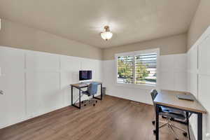 Office area featuring a decorative wall, a wainscoted wall, wood finished floors, and a textured ceiling