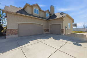 View of front of property featuring stone siding, stucco siding, and driveway