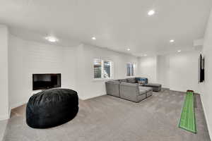 Living room with a textured ceiling, light carpet, and recessed lighting