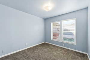 Den or Office, Add a closet to make a 3rd bedroom. Empty room featuring dark carpet and baseboards