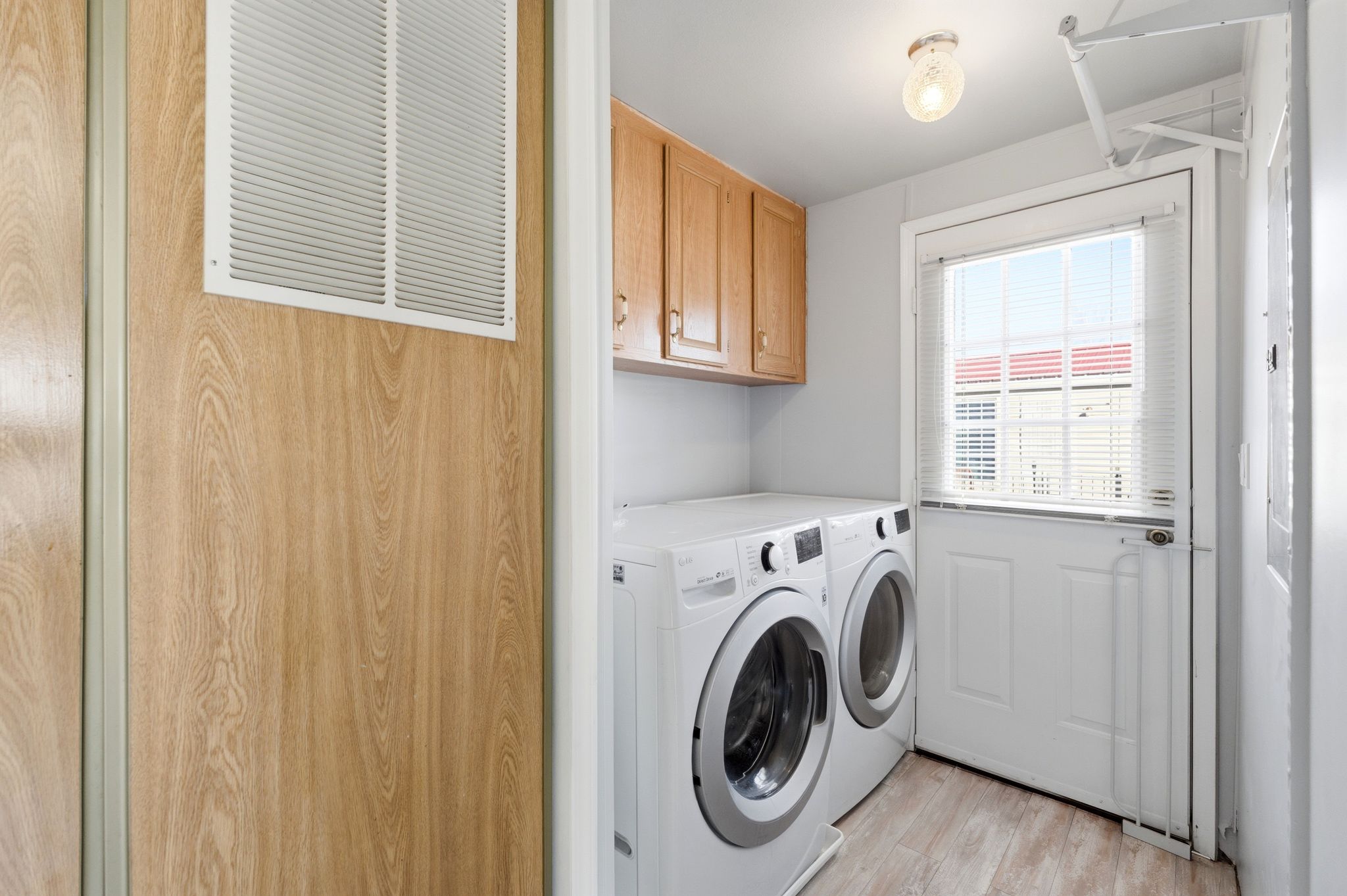 Laundry area with separate washer and dryer, light wood finished floors, and cabinet space