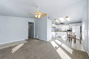 Unfurnished living room with light carpet, ceiling fan, and lofted ceiling