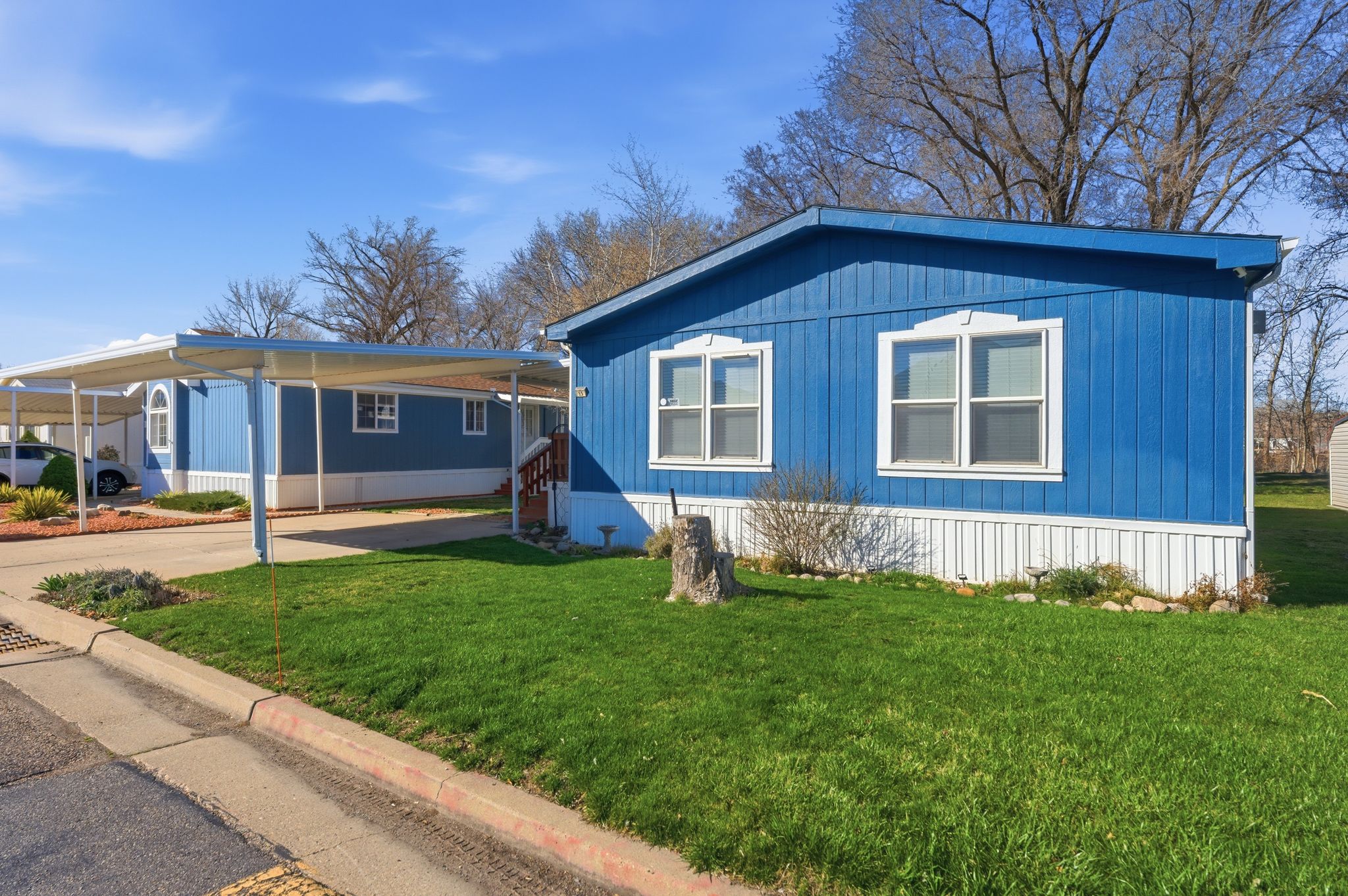 Manufactured / mobile home featuring a carport, a front yard, and concrete driveway