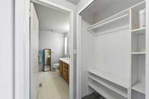 Closet and Bathroom featuring light flooring and vanity