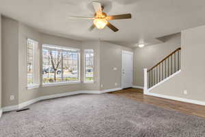 Carpeted foyer with stairs and ceiling fan