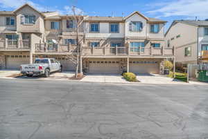 View of rear of property with stone siding, 2-car garage, concrete driveway, and a residential view