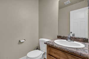 Half bathroom featuring vanity and toilet