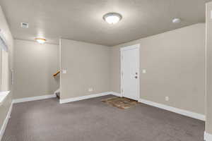 Spare room with a textured ceiling and dark carpet