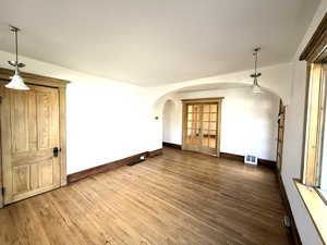 Empty room with dark wood-style floors and arched walkways