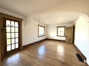 Spare room featuring arched walkways and dark wood-type flooring