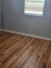 Spare room featuring dark wood-style floors and baseboards